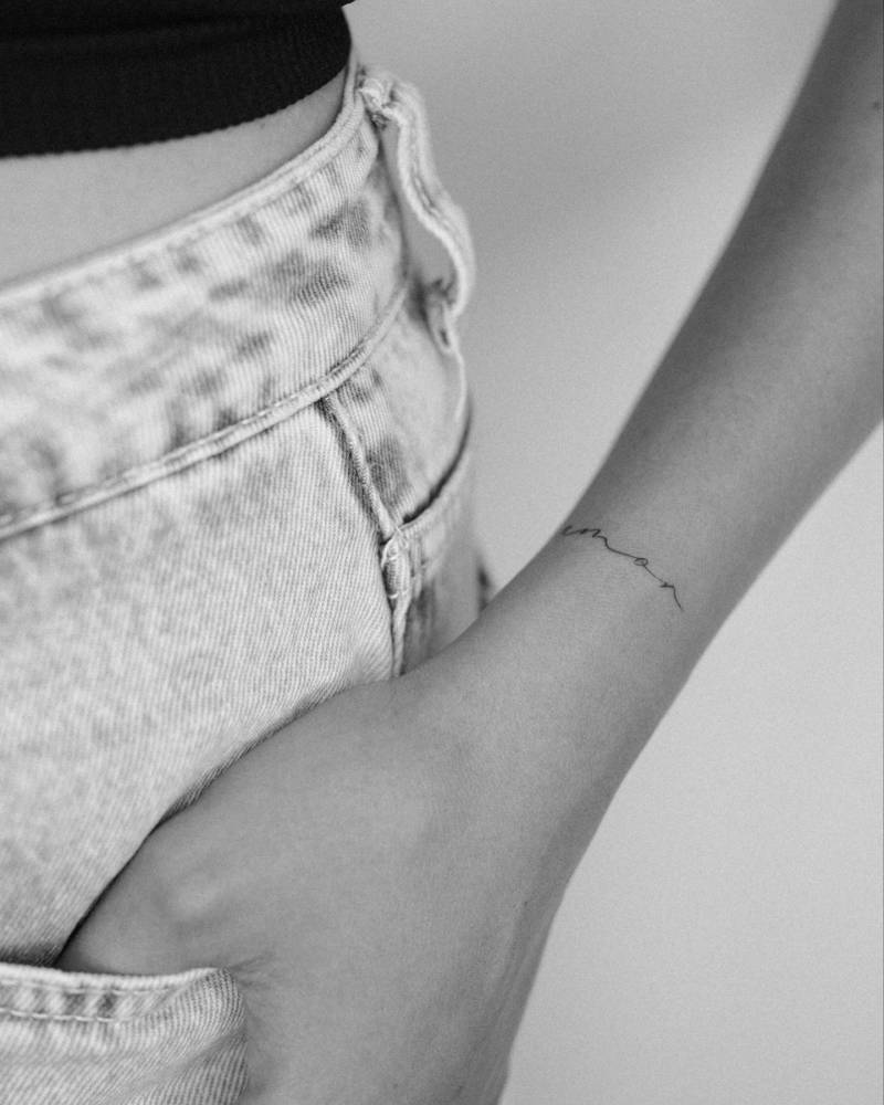 Little lettering tattoo of the word "amor" located on the wrist.