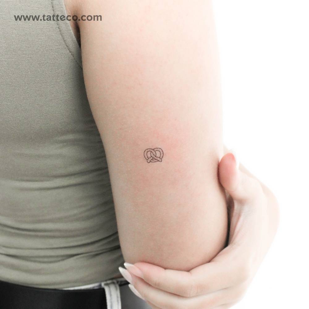 Tiny fine line pretzel temporary tattoo located on the tricep.