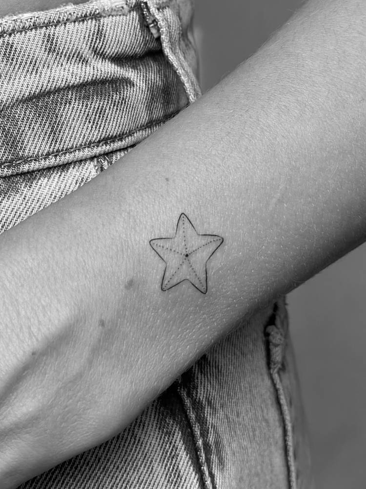 Starfish tattoo located on the wrist, illustrative style.