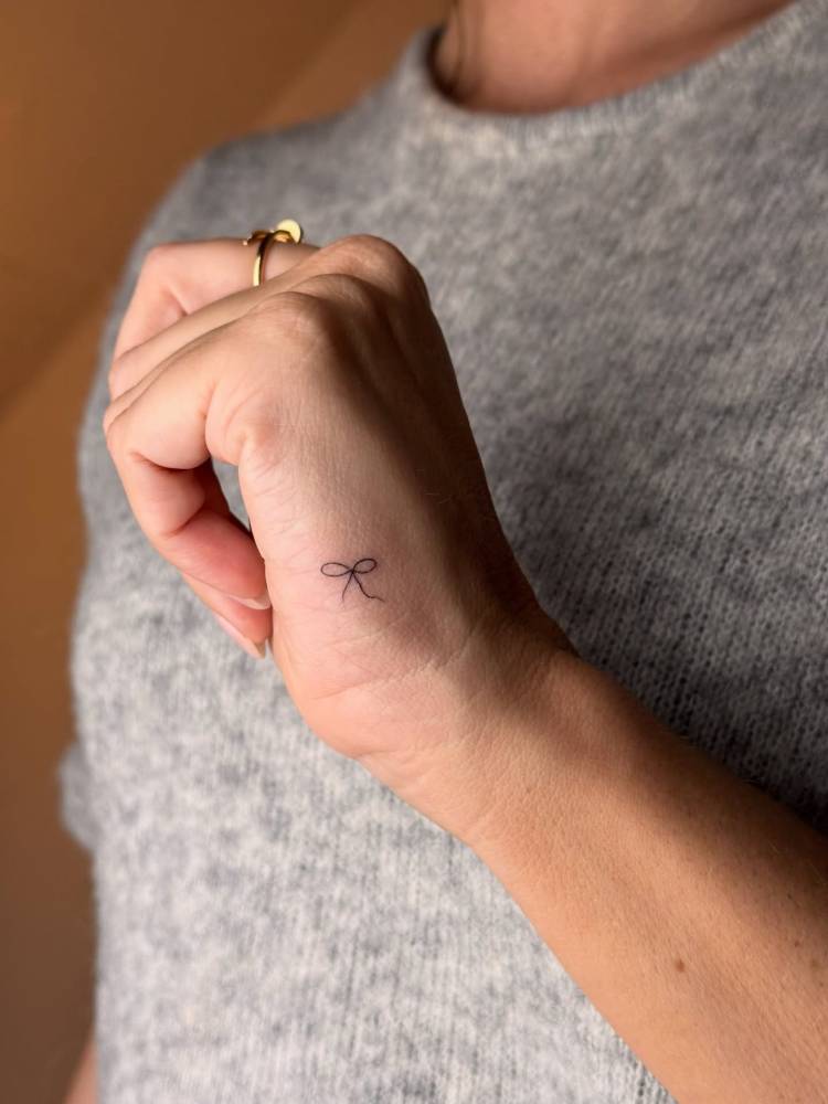 Minimalistic style bow tattoo done on the hand.