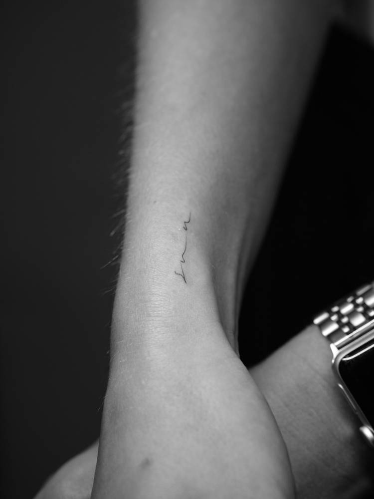 "Sun" lettering tattoo located on the wrist.