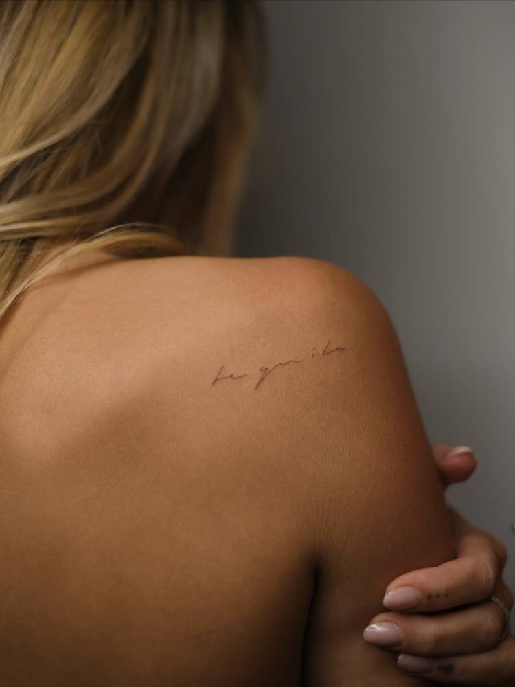 "Tequila" lettering tattoo handwritten on the shoulder blade.