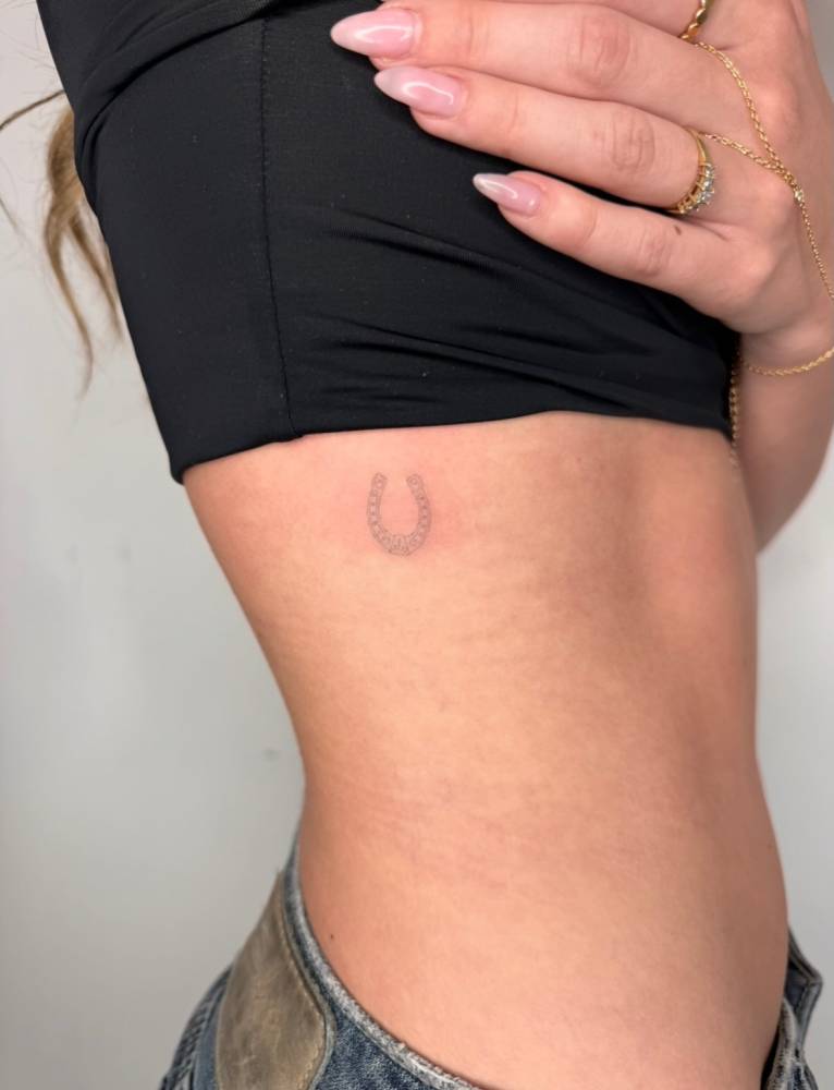 Horseshoe tattoo located on the rib, fine line style.