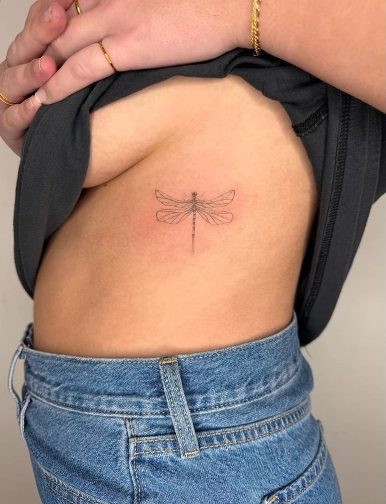 Single needle dragonfly tattoo located on the rib.