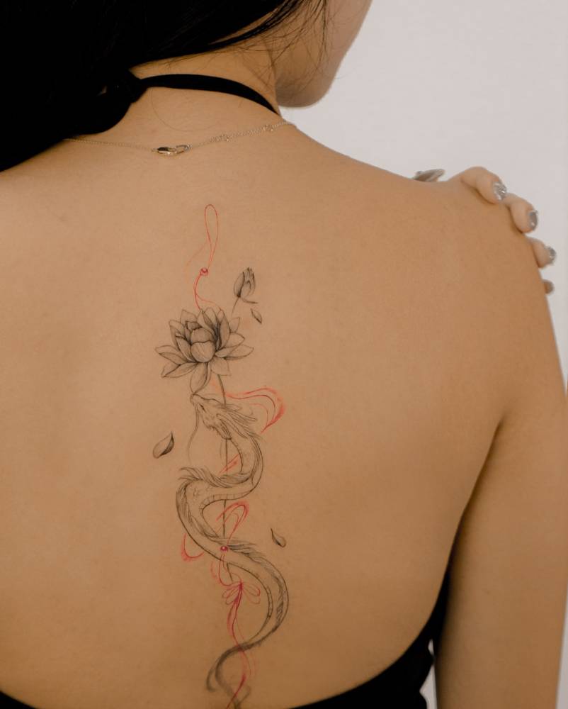 Illustrative style lotus flower tattoo located on the spine.