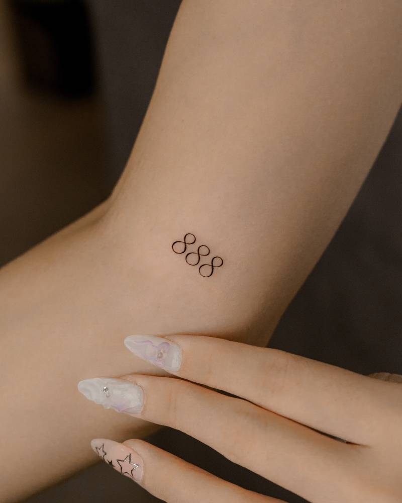 Angel number "888" tattooed on the inner arm.