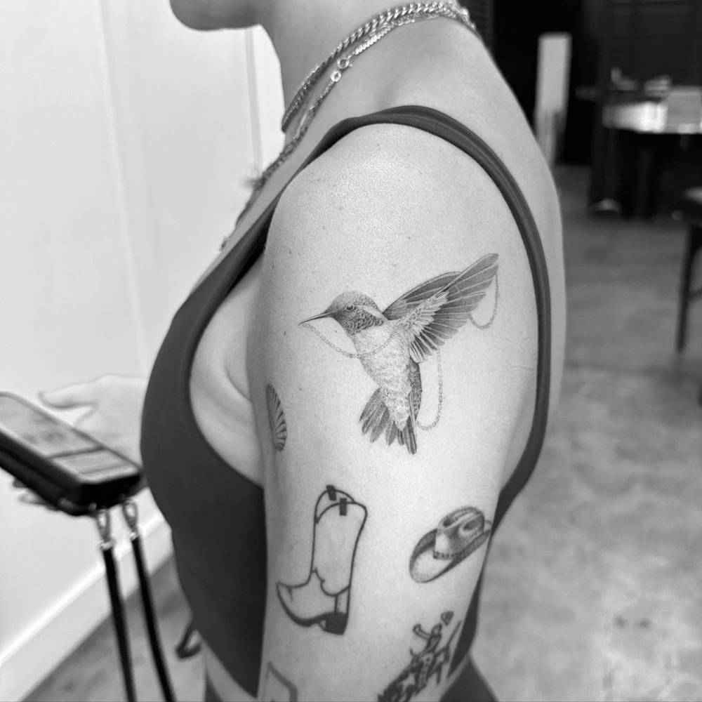 Micro-realistic style hummingbird tattoo located on the upper arm.