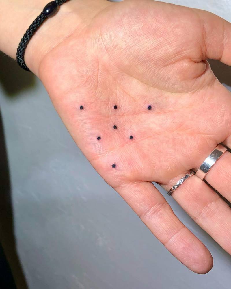 Minimalistic style dots tattooed on the palm.