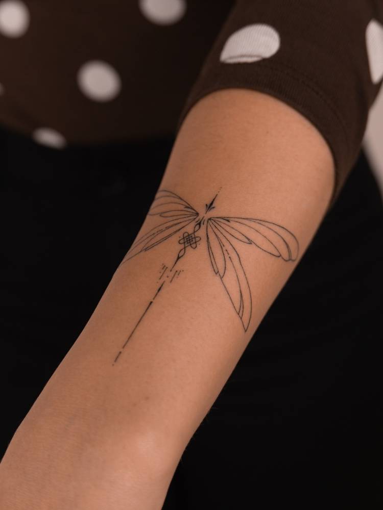 Ornamental dragonfly tattoo hand poked on the forearm.