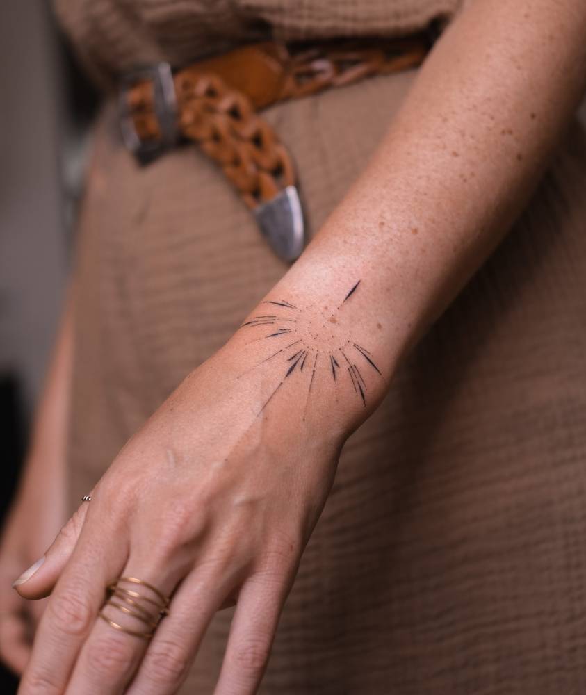 Hand poked style ornament tattooed on the wrist.