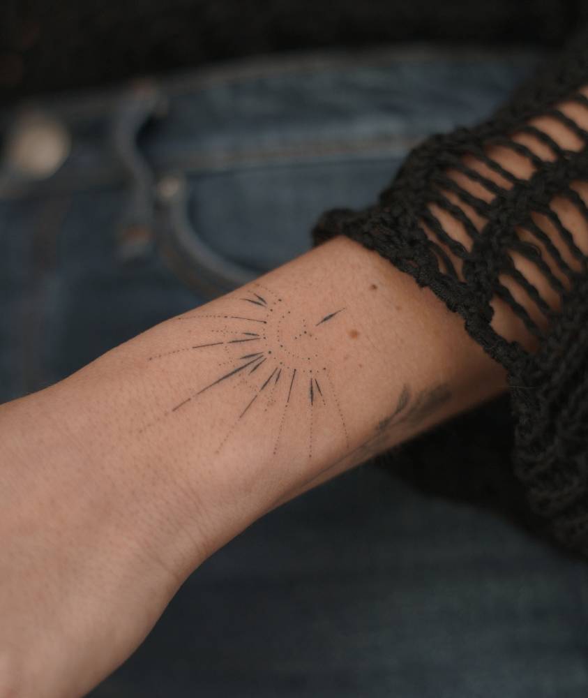 Hand poked style ornament tattoo placed on the wrist.