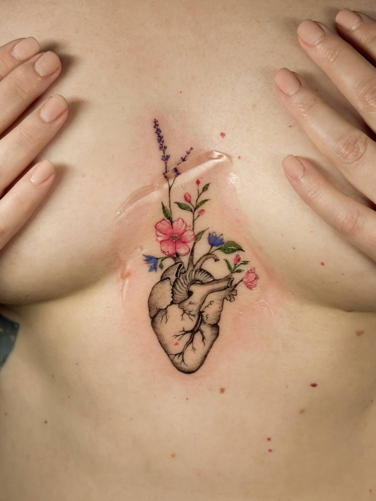 Anatomical heart and flower tattoo located on the sternum.