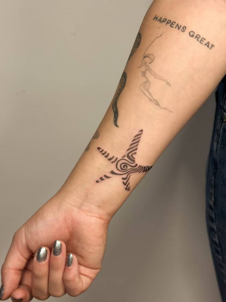 Abstract style starfish tattoo placed on the wrist.