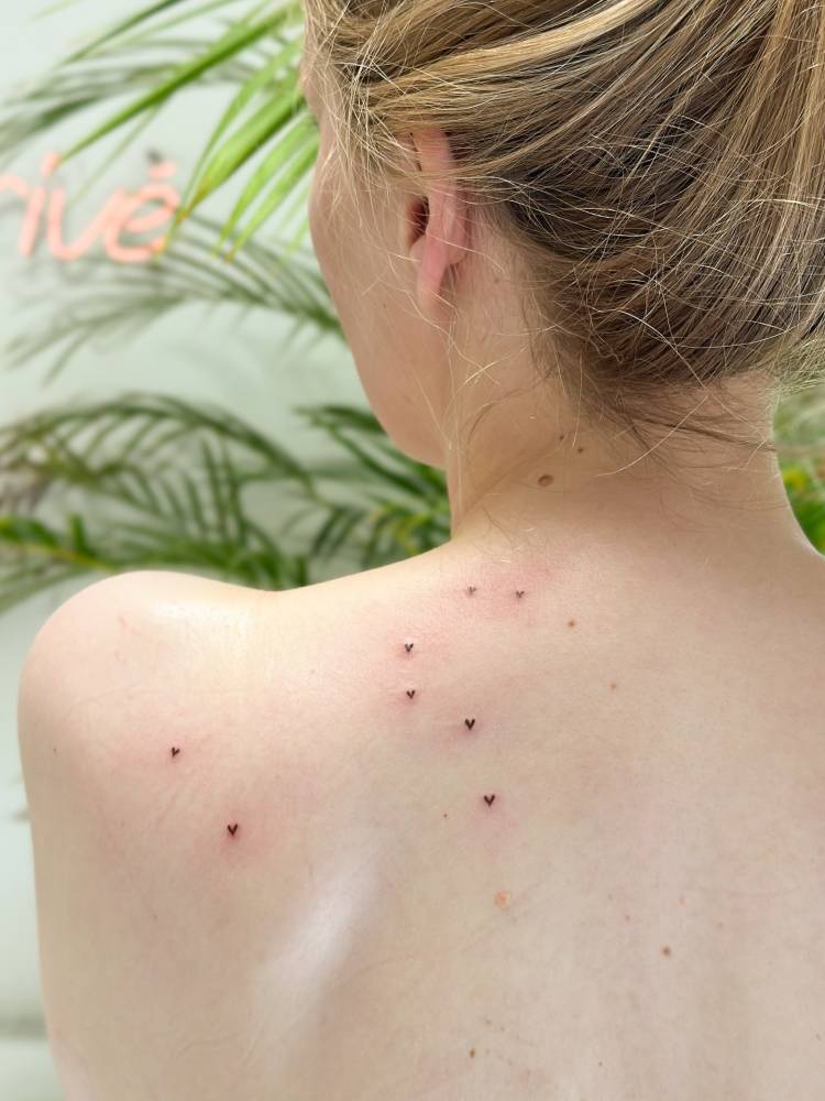 Minimalistic style heart freckles tattoo located on the shoulder blade.