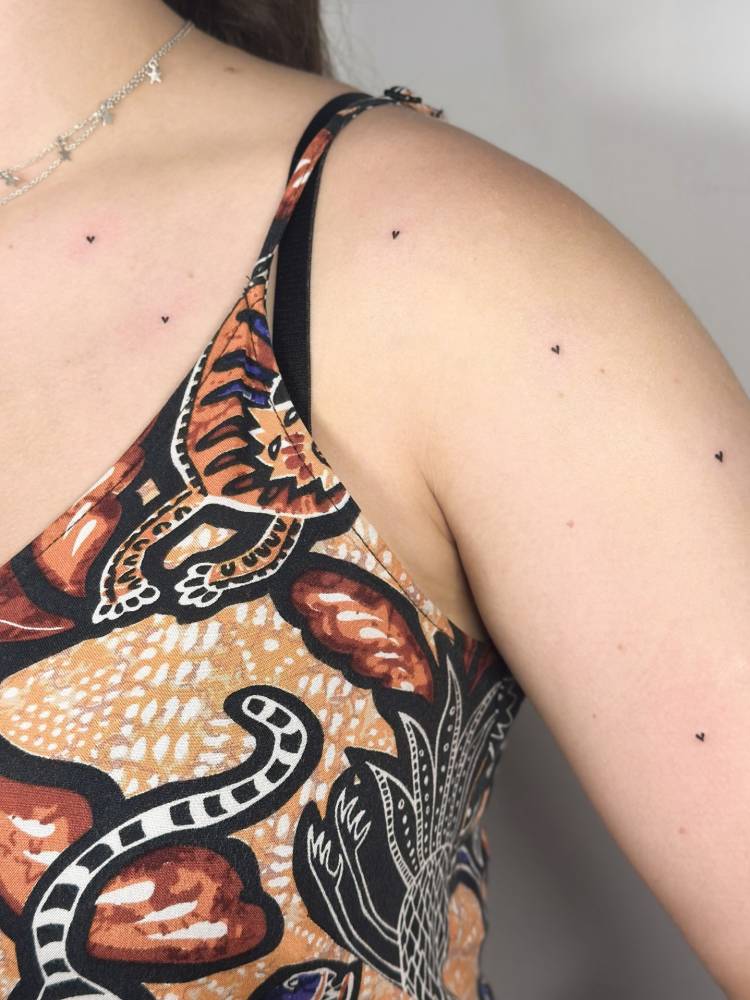 Heart freckles tattooed on the upper arm and shoulder.