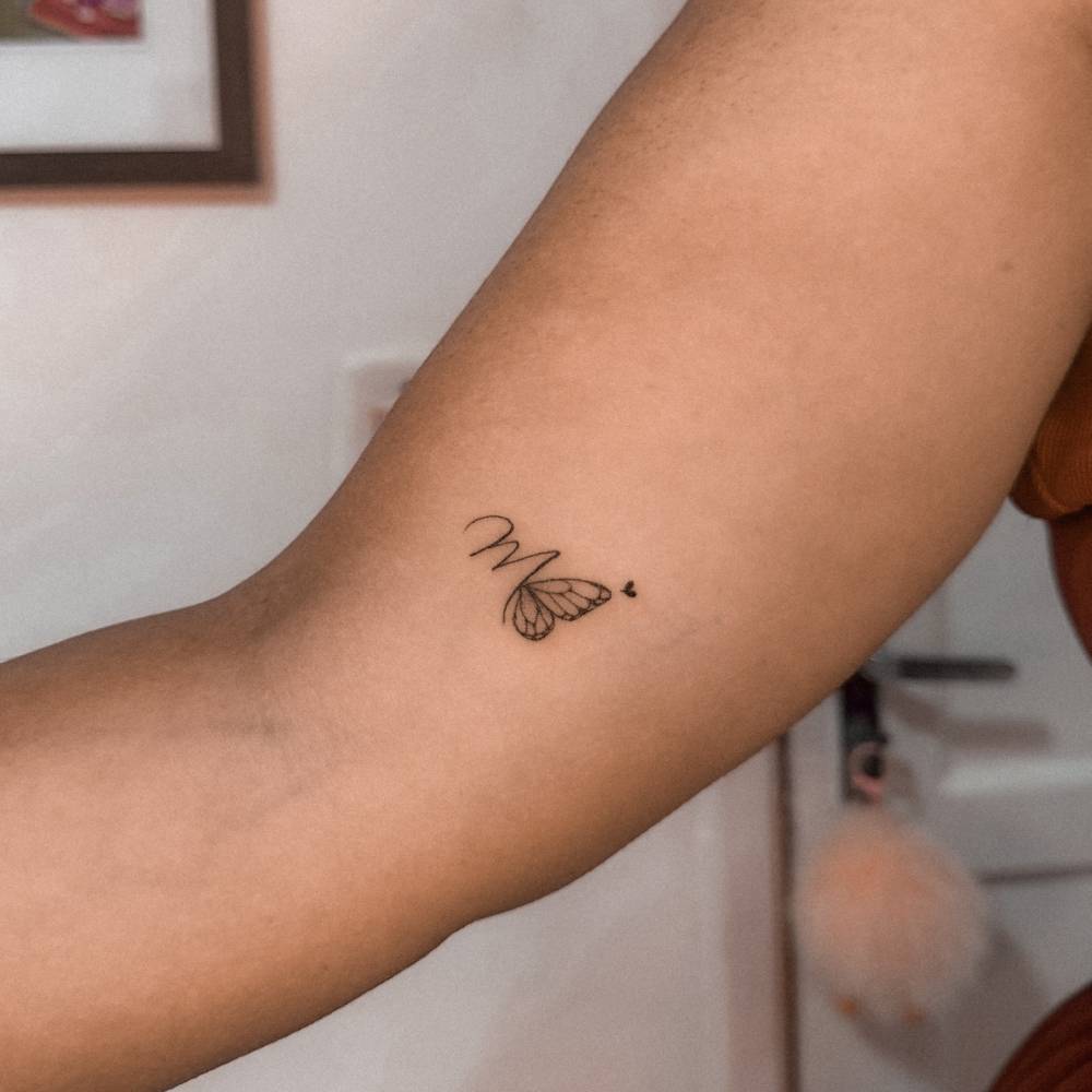 Letter "M" and butterfly tattoo located on the inner arm.
