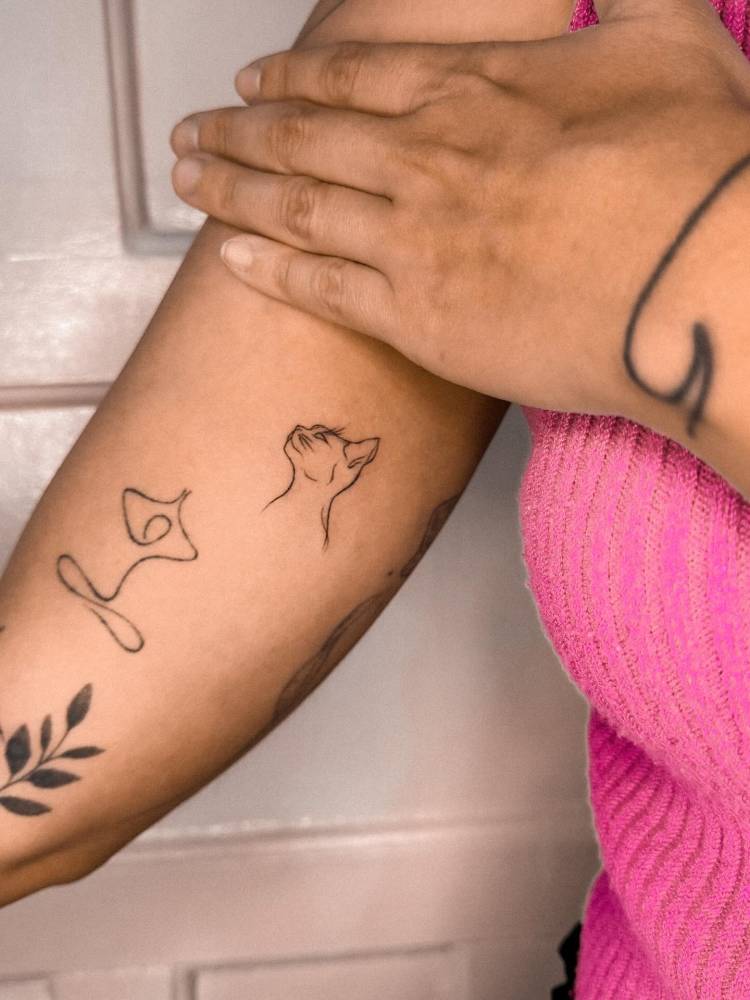 Fine line style cat portrait tattoo located on the inner arm.