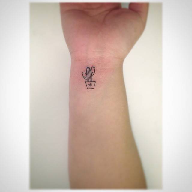 Minimalistic style cactus tattoo located on the wrist.