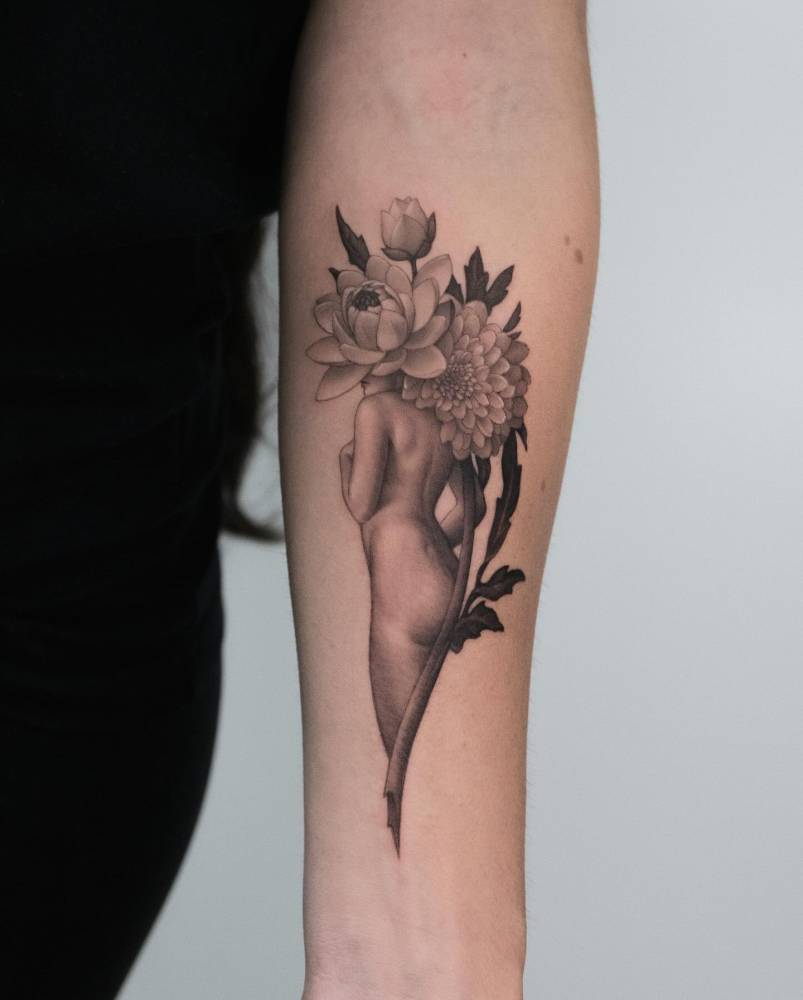 Flower head woman tattoo in micro-realistic style located on the inner forearm.