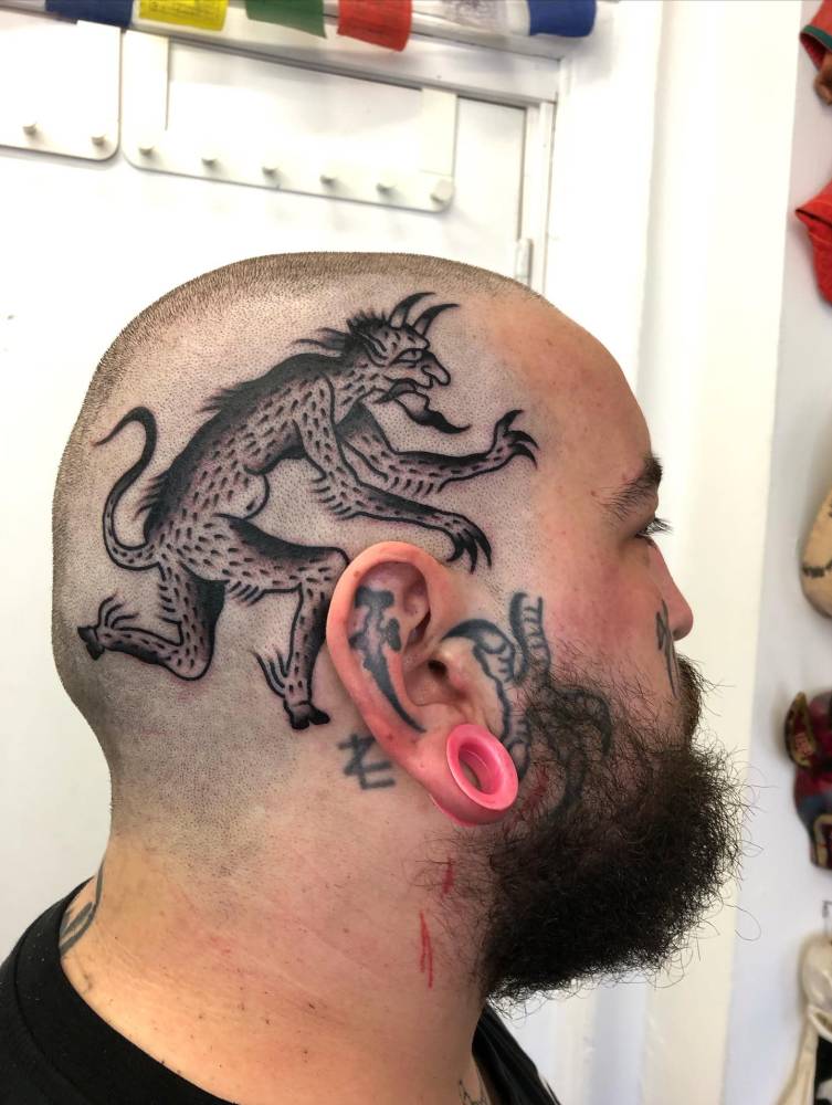 Blackwork style devil tattoo located on the head.