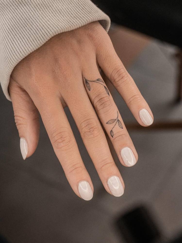 Tiny leaves tattoo in minimalistic style placed on the finger.