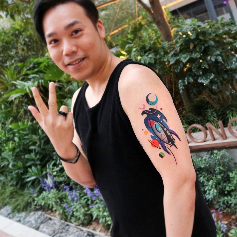 Pop art style rocket tattoo located on the upper arm.