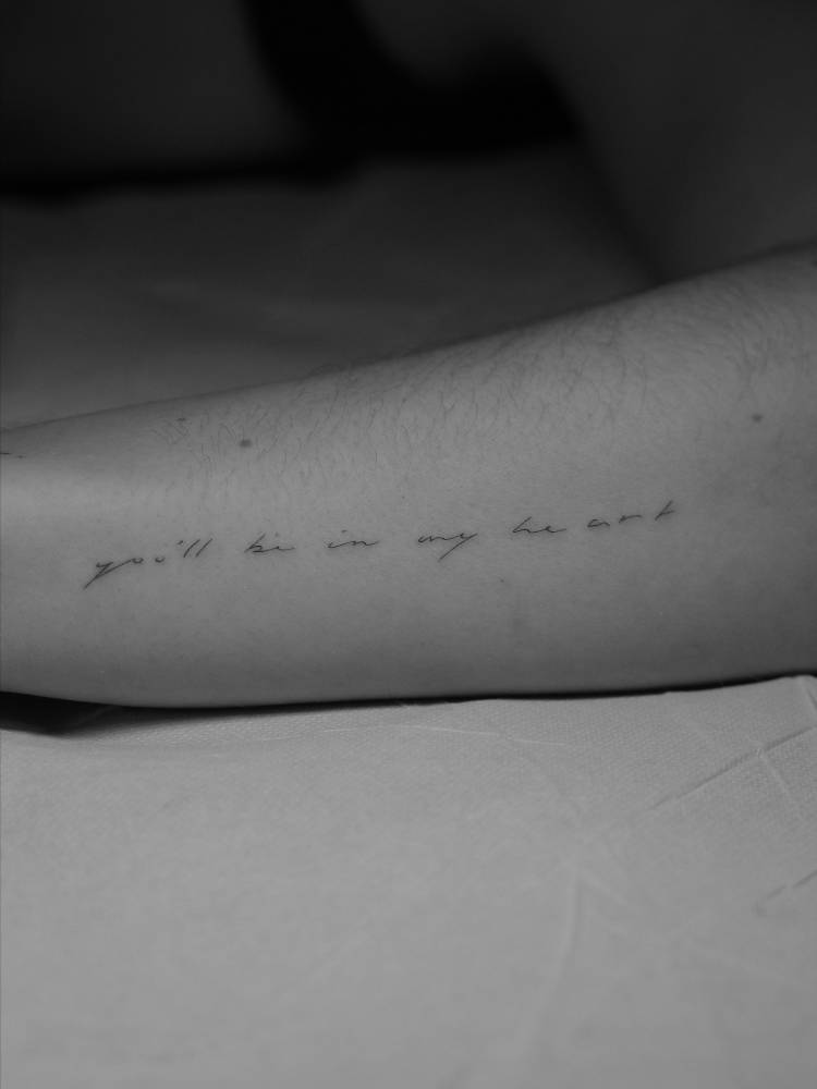 Handwritten font "you‘ll be in my heart" lettering tattoo located on the forearm.