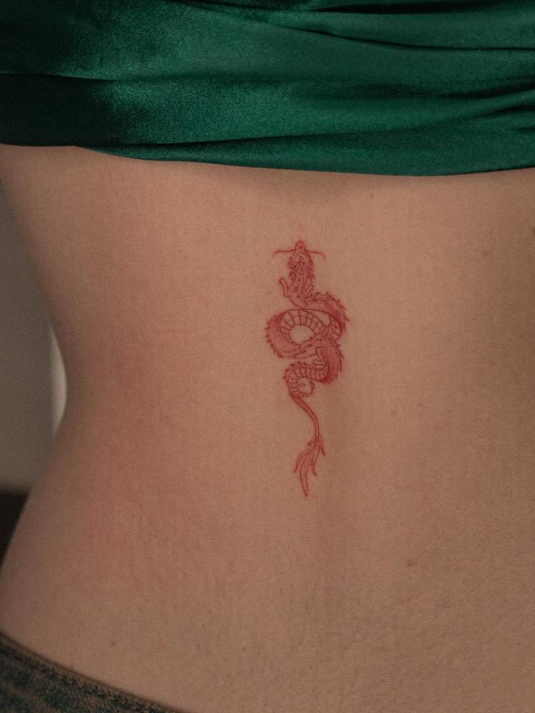 Fine line style red dragon tattoo located on the lower back.