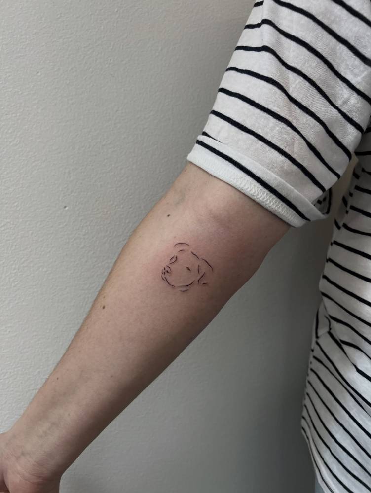 Dog portrait tattoo in minimalistic style located on the inner forearm.