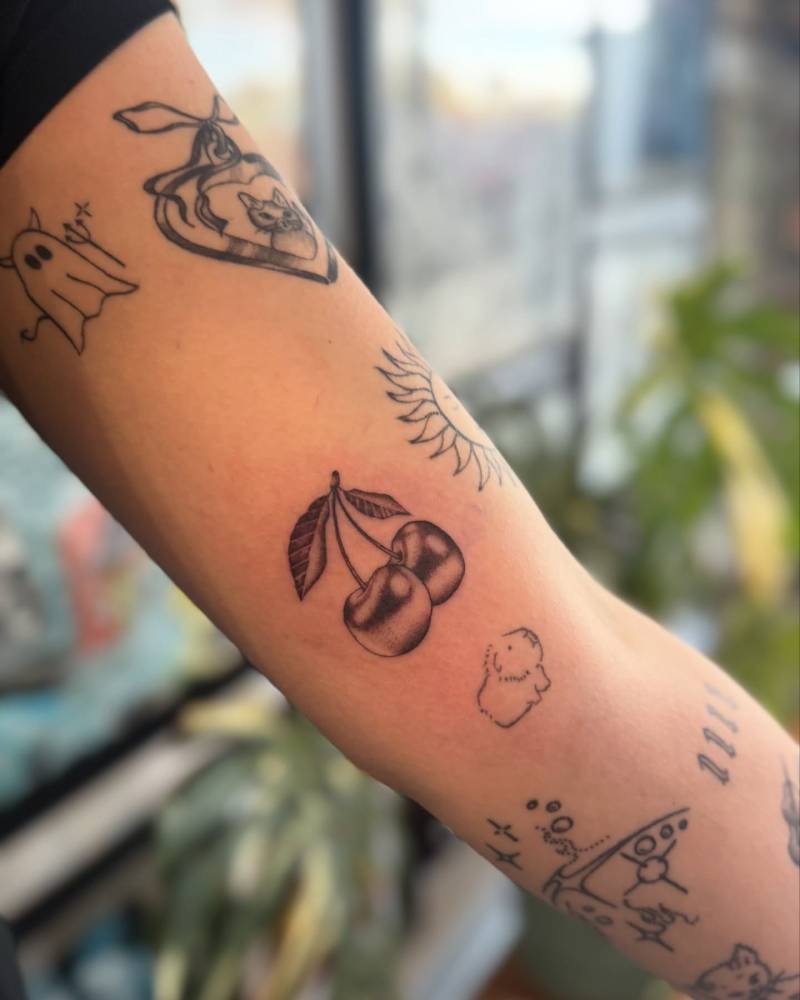 Illustrative style cherries tattoo located on the inner arm.