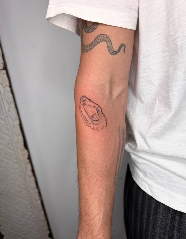 Oyster tattoo located on the inner forearm, illustrative style.