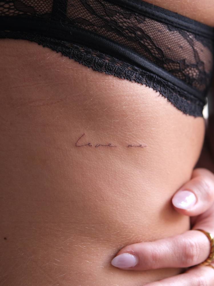 Handwritten font words "love me" tattooed on the back.