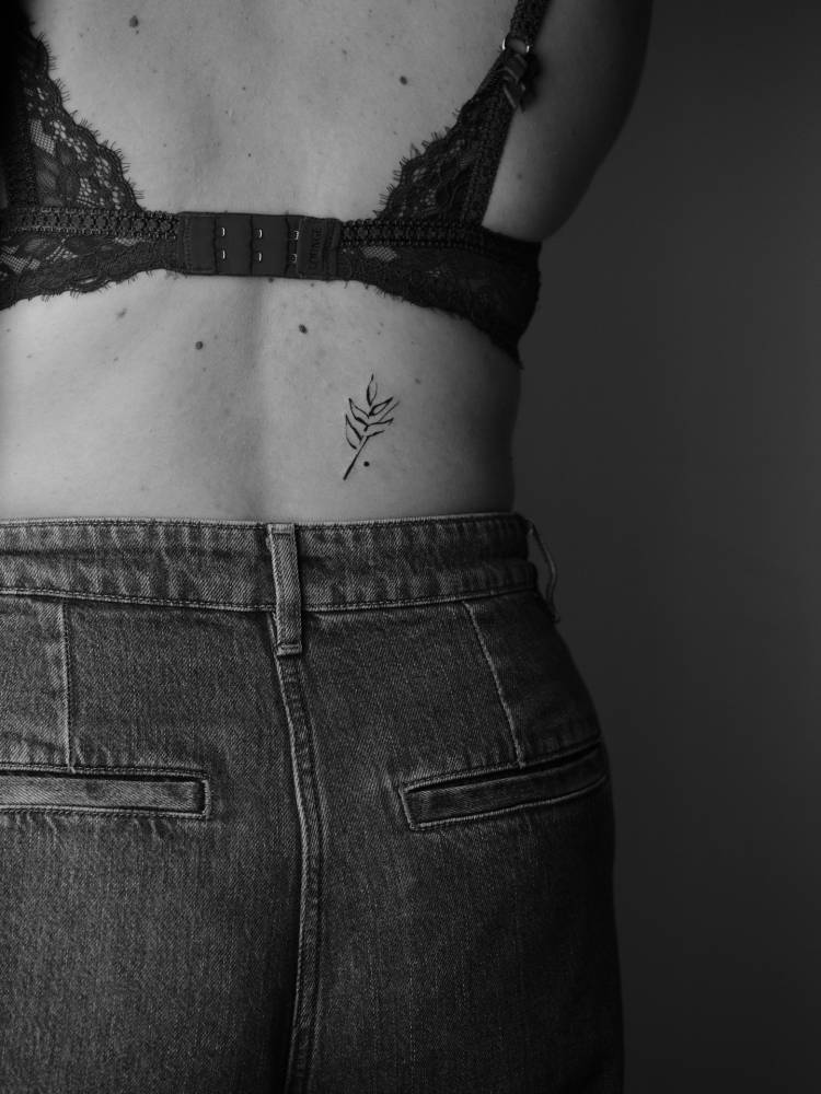 Leaves tattoo located on the lower back, illustrative style.