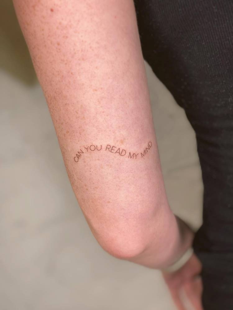 "Can you read my mind" lettering tattoo located on the tricep.
