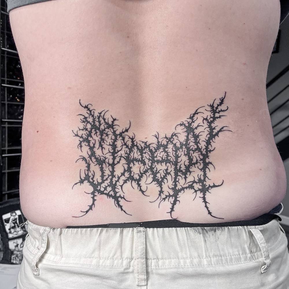 Tribal lettering word "sleepy" tattooed on the lower back.