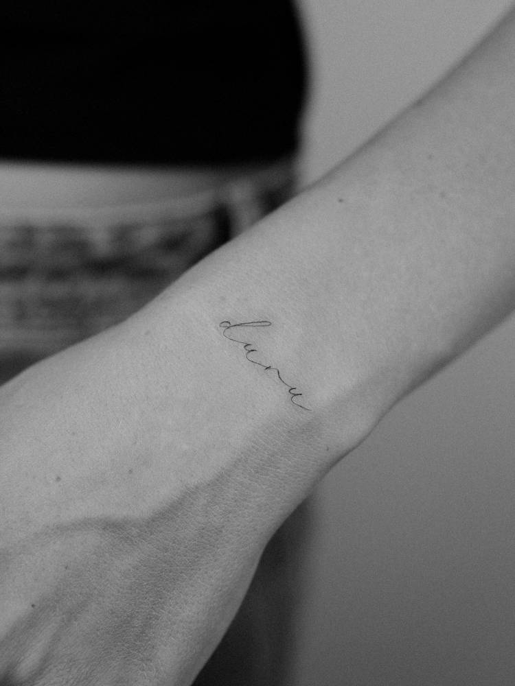 Script font name "Duru" tattoo located on the wrist.