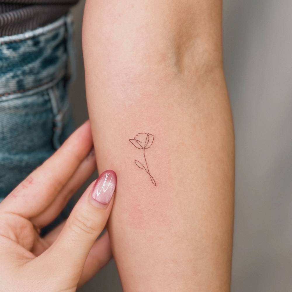 One line poppy flower tattoo located on the inner forearm.