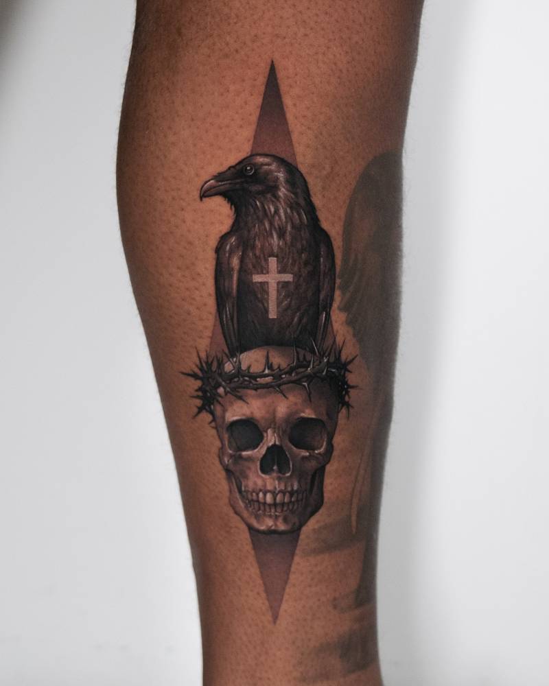 Black and grey crow and skull tattoo located on the shin.