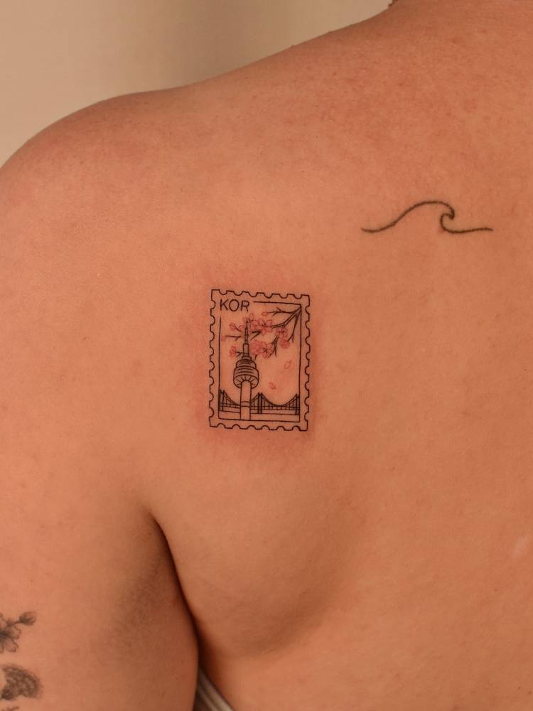 N Seoul Tower stamp tattoo located on the shoulder blade.