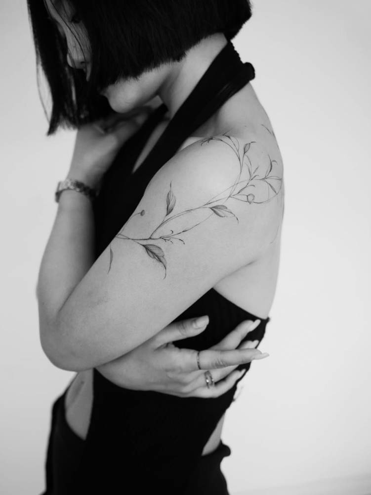 Leaves tattoo located on the shoulder, illustrative style.