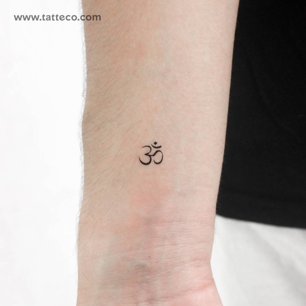 Tiny minimalistic Om temporary tattoo located on the wrist.