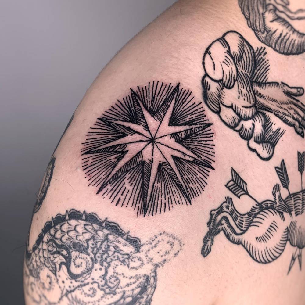 Star tattoo in engraving style located on the shoulder.