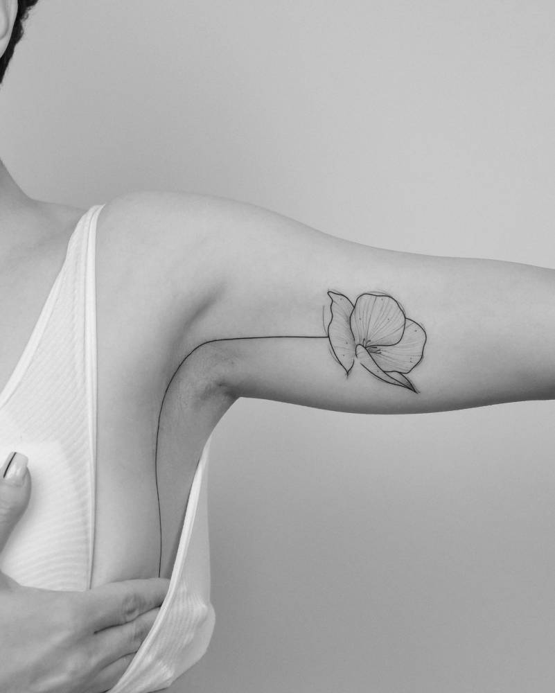 Poppy flower tattoo in illustrative style located on the armpit and inner arm.