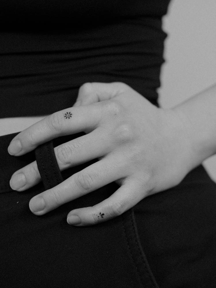 Minimalistic flower and ornament tattoos placed on the fingers.