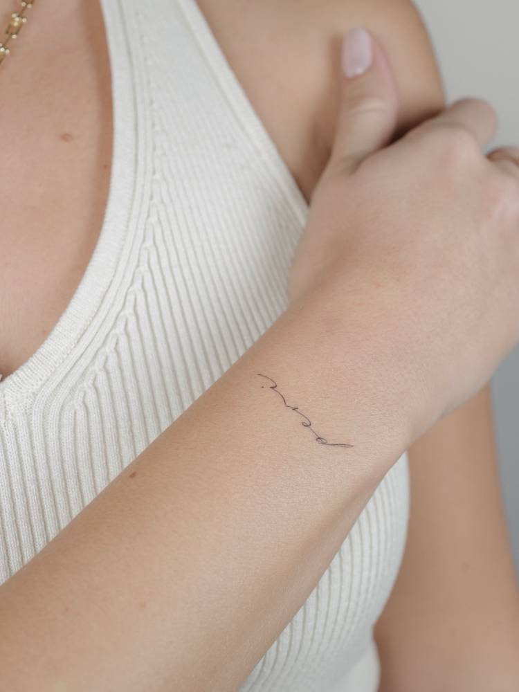 Lettering tattoo of the word "peri" located on the wrist.