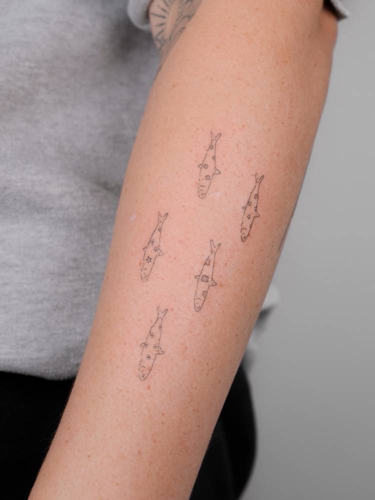 Floral fish collection tattooed on the forearm.