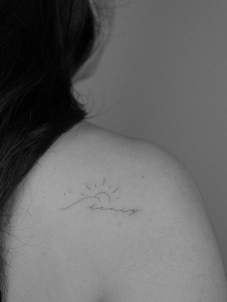 Name "Deniz" sea sunset tattoo located on the shoulder blade.