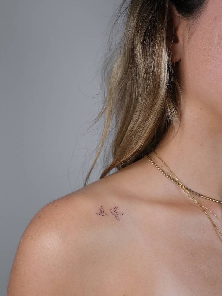 Cute flying birds tattoo in minimalistic style located on the collarbone.