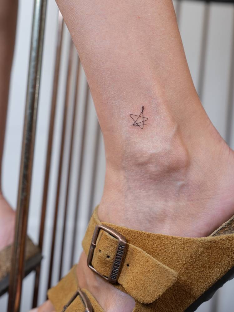 One line star tattoo located on the ankle.
