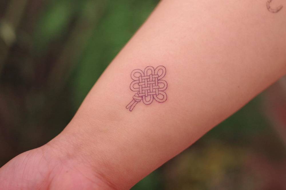Korean knot tattoo in fine line style located on the wrist.